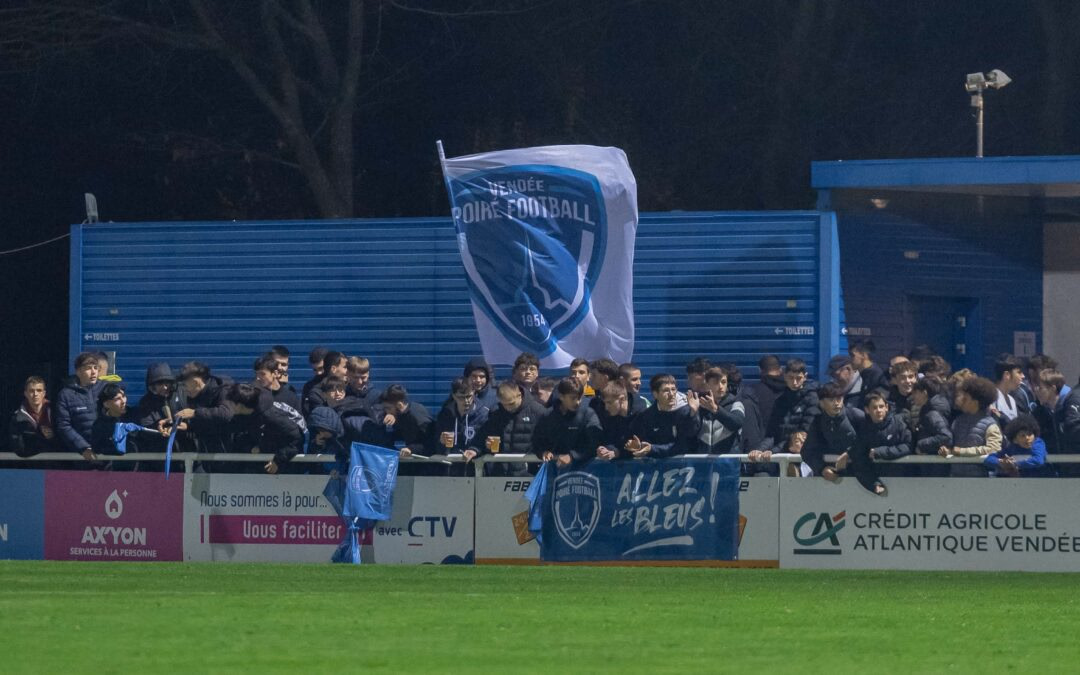 Drapeau de supporter XXL aux couleurs d'un club déployé dans une tribune de football