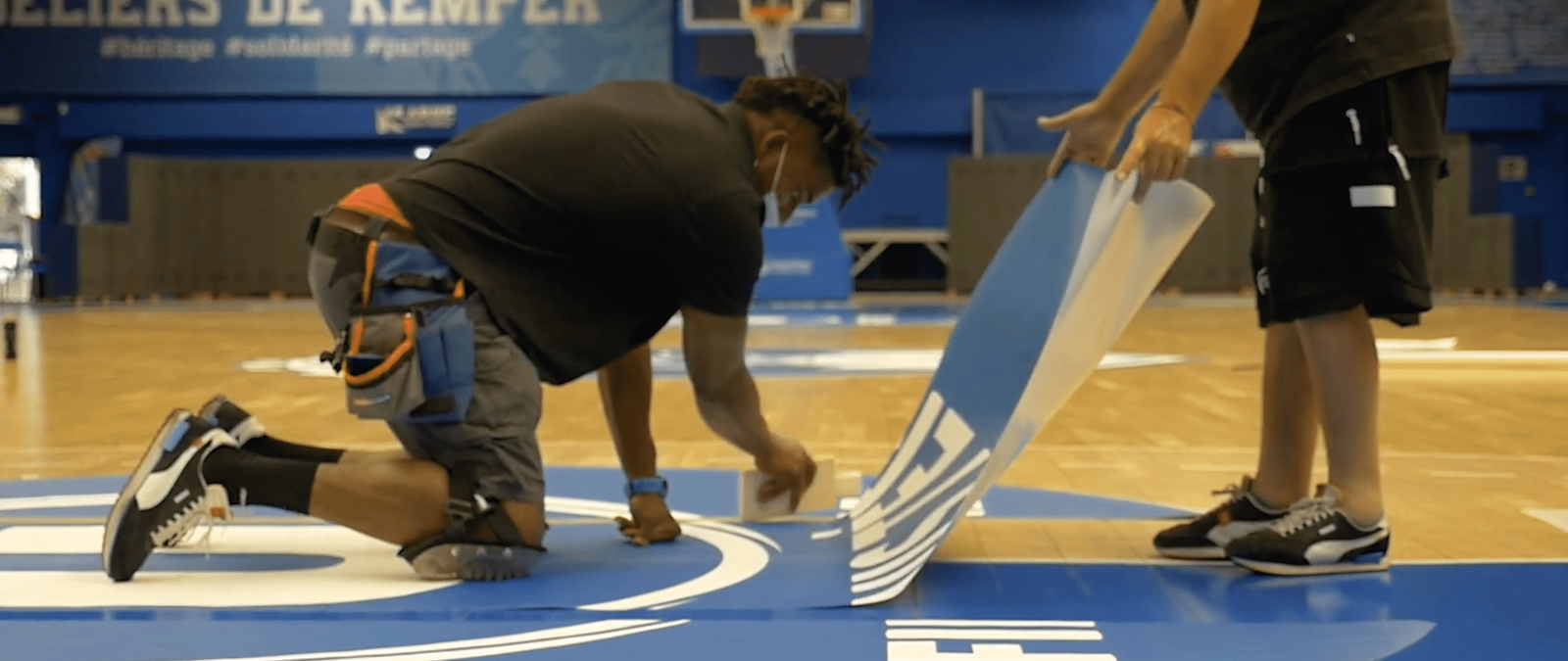 Pose d'un sticker de sol repositionnable IND'N'GO® sur un parquet de basket — Nakara Sport