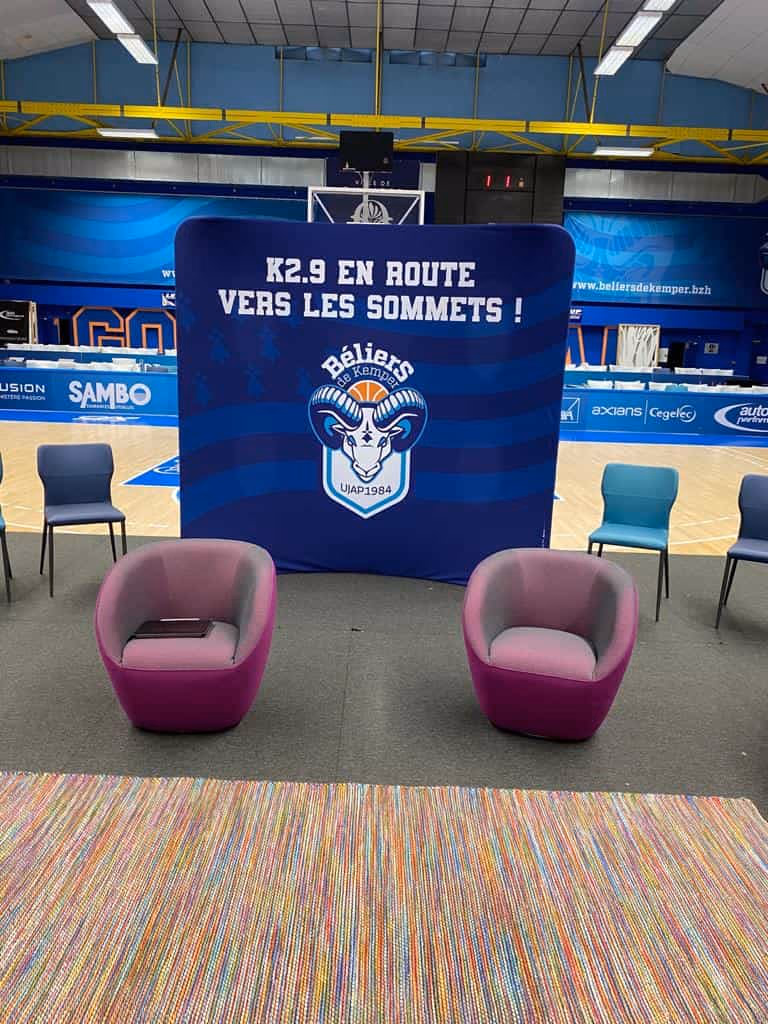 Mur d'interview de l'UJAP Quimper basket : joueur en interview d'après-match devant le photocall du club