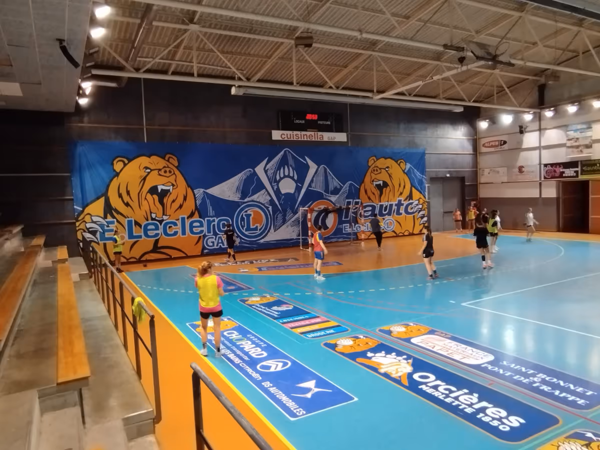 Panneaux publicitaires toblerone en bord de terrain de basket, tribune animée | Nakara Sport
