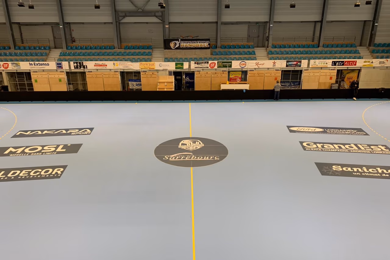Sol sportif Gerflor Taraflex gris avec marquage et rond central en salle de handball (Sarrebourg) - Nakara Sport